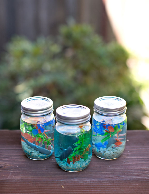 Make Real-Looking Aquariums by adding plants, rocks, and aquarium figurines to a mason jar of blue water. 
