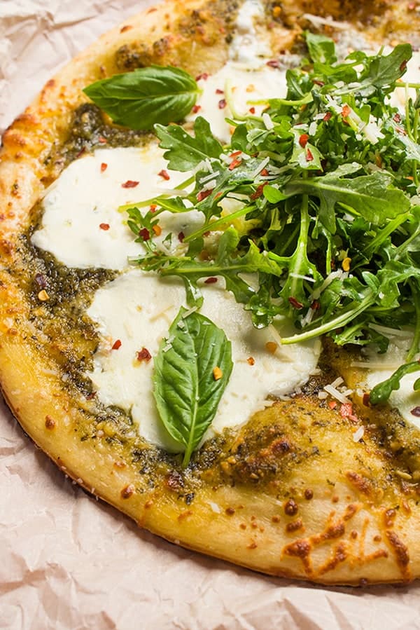 This fast and easy grilled pizza recipe is made with bright pesto, fresh mozzarella and topped with a lemony arugula salad.