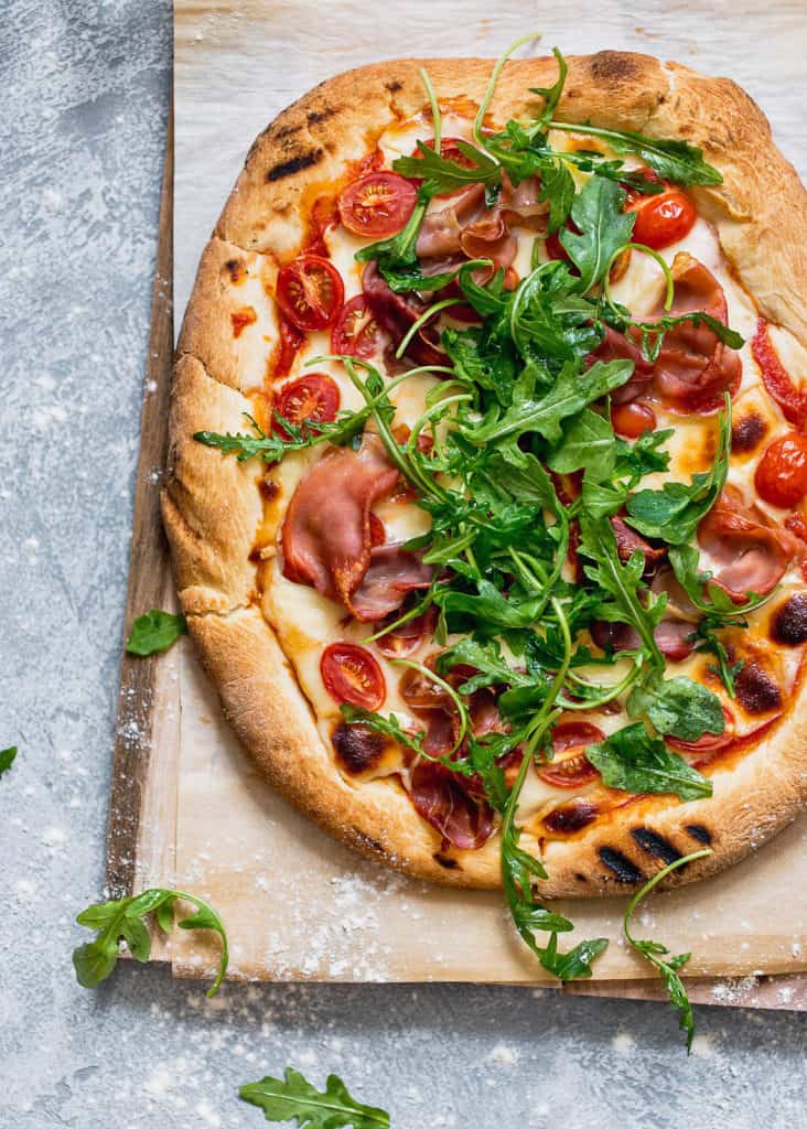 Grilled Prosciutto Arugula Pizza Recipe- A delicious and irresistible smokey pizza with a 4 cheese blend, salty prosciutto and crispy arugula.